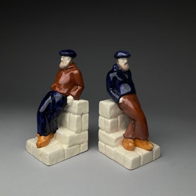 pair of ceramic figurines of two men sitting on blocks