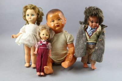 three dolls sitting next to each other on a gray surface
