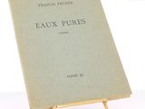 un vieux livre posé sur un support métallique sur une surface blanche