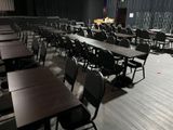 many tables and chairs in a room with black walls