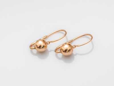 une paire de boucles d'oreilles en forme de boules dorées sur fond blanc