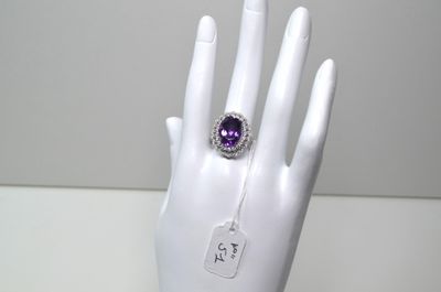 une image représentant une main blanche avec une bague violette au doigt