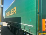 a green semi truck that is parked next to a pole