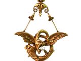a gold bird hanging from a wire with a pearl