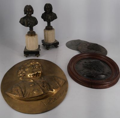 three bronze busturines and a mirror on a white surface