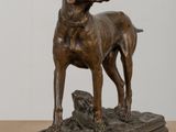 bronze statue of a dog standing on top of a wooden table