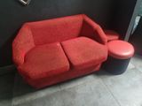 un canapé rouge et un tabouret dans un coin de la pièce
