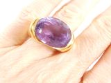 someone is holding a ring with a large purple stone on it