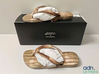 quelqu'un porte une paire de sandales posées sur une planche en bois