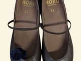 a pair of black shoes with a blue pom pom on them