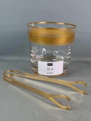 un verre à bord doré et une paire de pinces