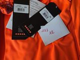 une chemise orange posée sur un banc en bois, à côté d'une paire de ciseaux