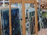 une pièce remplie de matériel artistique et où sont exposées des peintures