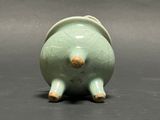 a small green vase with a gold decoration on the top