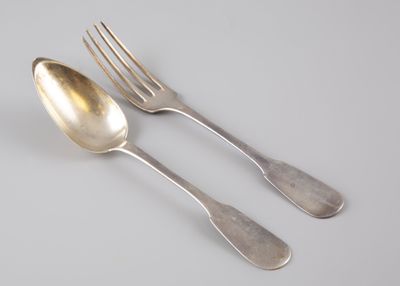 deux cuillères et une fourchette en argent sur une surface blanche