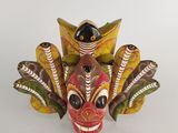 a close up of a wooden mask with feathers on a white background