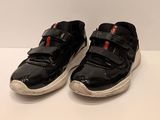 pair of children ' s black shoes with white soles on a white surface