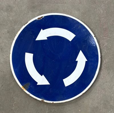 un panneau circulaire bleu et blanc sur lequel figurent des flèches