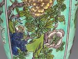 a green vase with flowers and birds painted on it