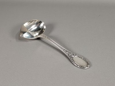 une cuillère en argent avec un manche de cuillère sur une table