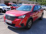 La voiture rouge est garée sur le parking, à côté de nombreuses autres voitures.
