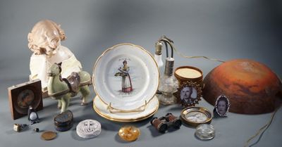 une figurine représentant un garçon assis sur une chaise, à côté d'une assiette et d'autres objets