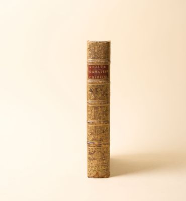 un vieux livre posé sur une table à côté d'un mur blanc