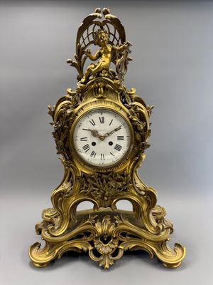 une horloge en or surmontée d'un oiseau