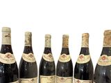 six bouteilles de vin sont alignées sur une surface blanche
