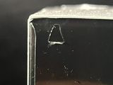 a hand holding a small square object with a hole in it