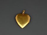 a close up of a gold heart pendant on a gray surface