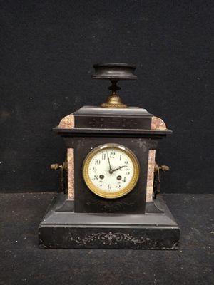 une petite horloge posée sur une table noire