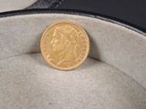une pièce d'or posée dans une boîte à chapeaux