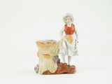 a figurine of a woman standing next to a tree stump