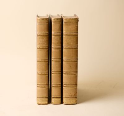 trois vieux livres posés l'un sur l'autre sur une surface blanche