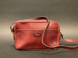 a red leather bag with a strap on a grey background