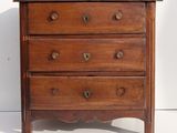a small wooden chest of drawers on a white floor