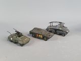 three toy army vehicles are lined up in a row on a white surface