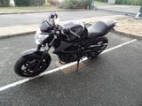 a black motorcycle parked in a parking lot next to a fence