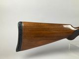 a close up of a wooden rifle on a white surface