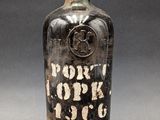an old bottle of liquor with a cork stopper sitting on a table