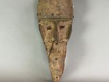 an old wooden mask hanging on a wall in a white room