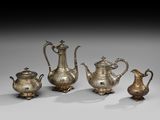 trois théières en argent et une cafetière, posées sur des socles