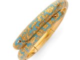 un gros plan d'un bracelet en or et turquoise sur fond blanc
