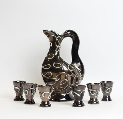 a pitcher and four cups sitting next to each other