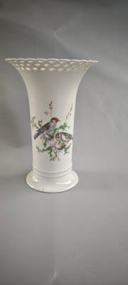 un vase blanc orné d'un oiseau, posé sur une table