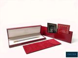 une boîte rouge contenant un stylo et un bloc-notes
