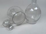 a glass bottle with a glass stopper next to a glass bottle with a glass stopper