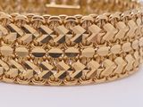 a close up of a gold bracelet on a white surface