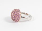 un gros plan d'une bague ornée de pierres roses sur un fond blanc